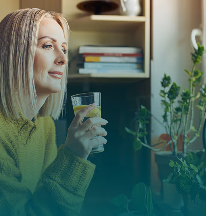 Woman holding a glass of water by a window